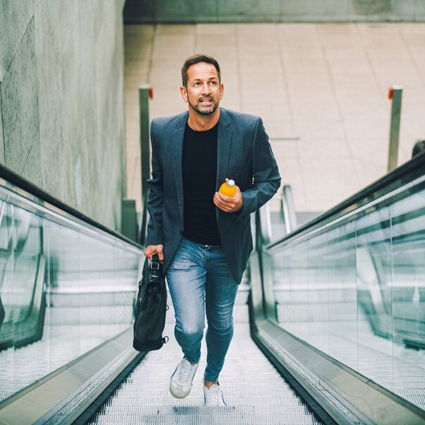 Casual business man runs up escalator