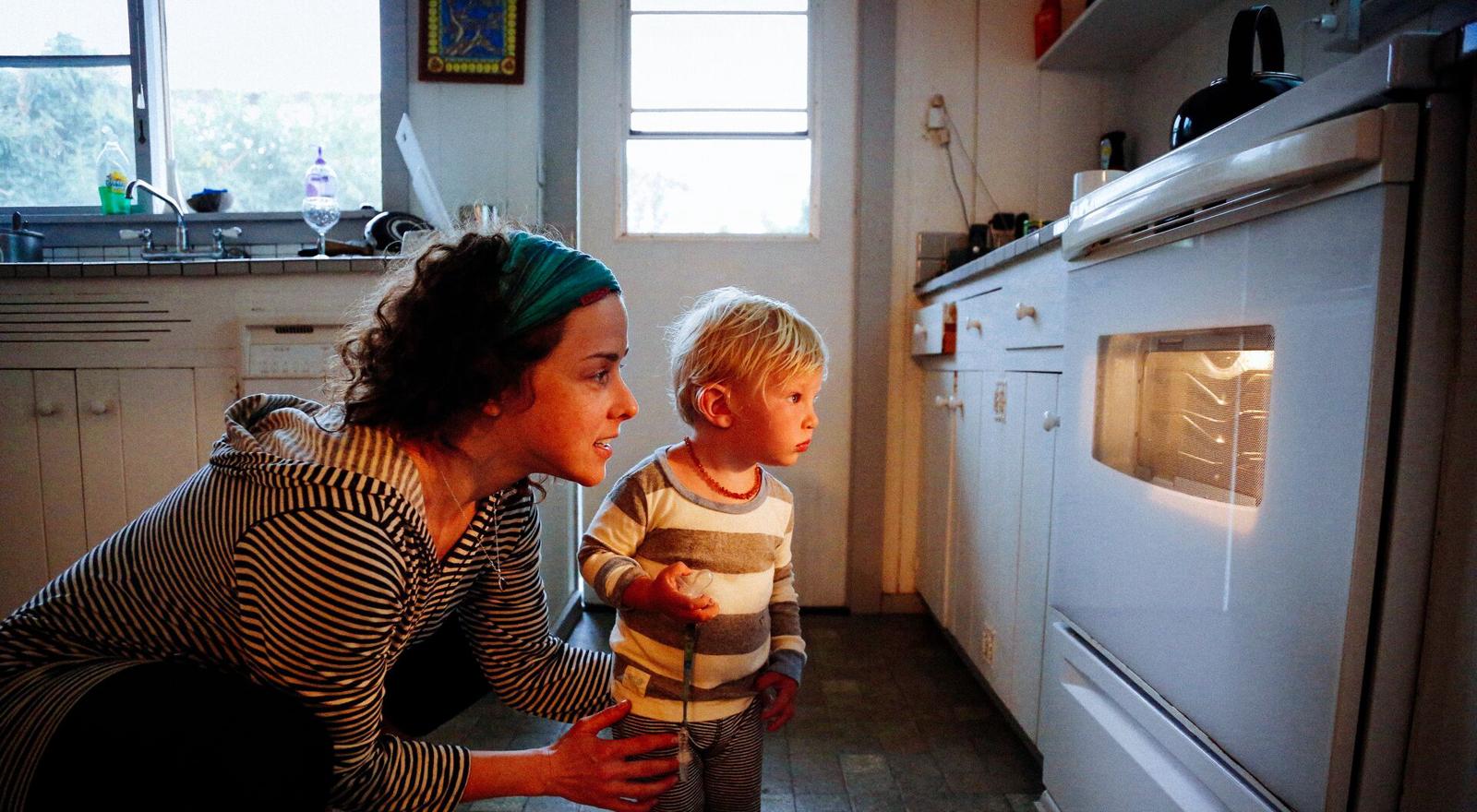 Large Web and Screen A woman and a young boy are watching food cook through the oven window in the kitchen
