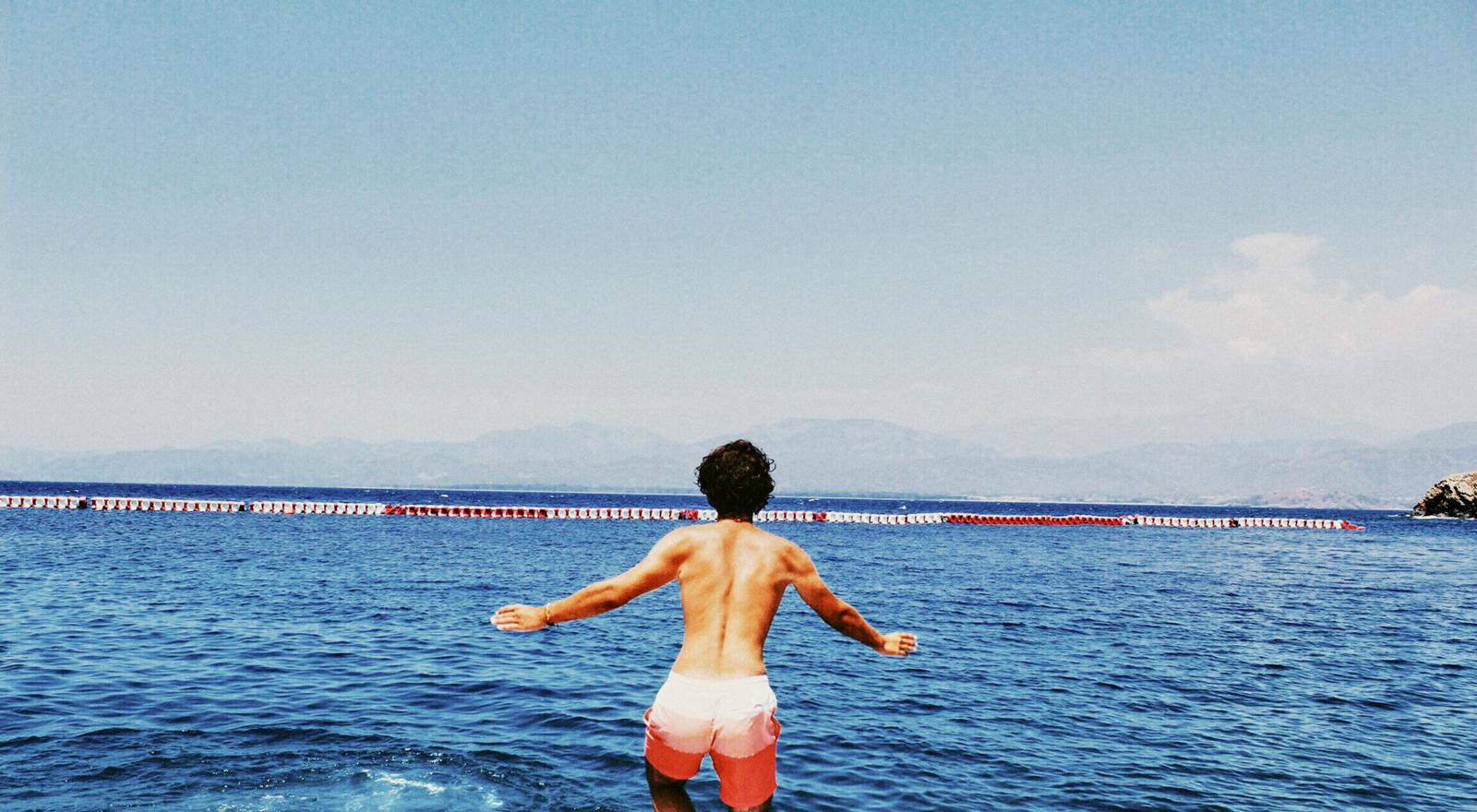 Large Web and Screen Back view of a man in swim shorts about to jump into the water
