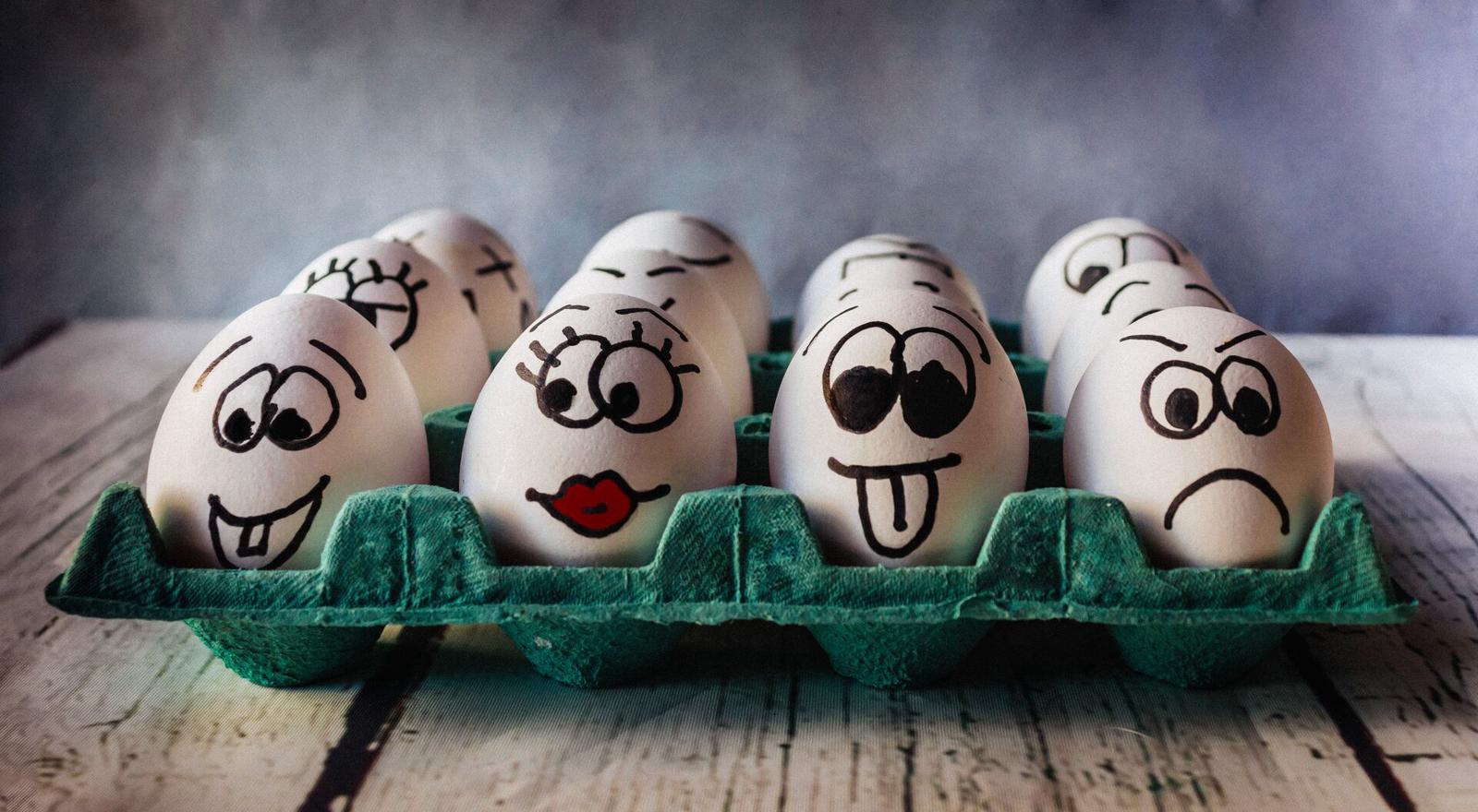 Large Web and Screen Close up of eggs in an egg carton with funny faces drawn on them
