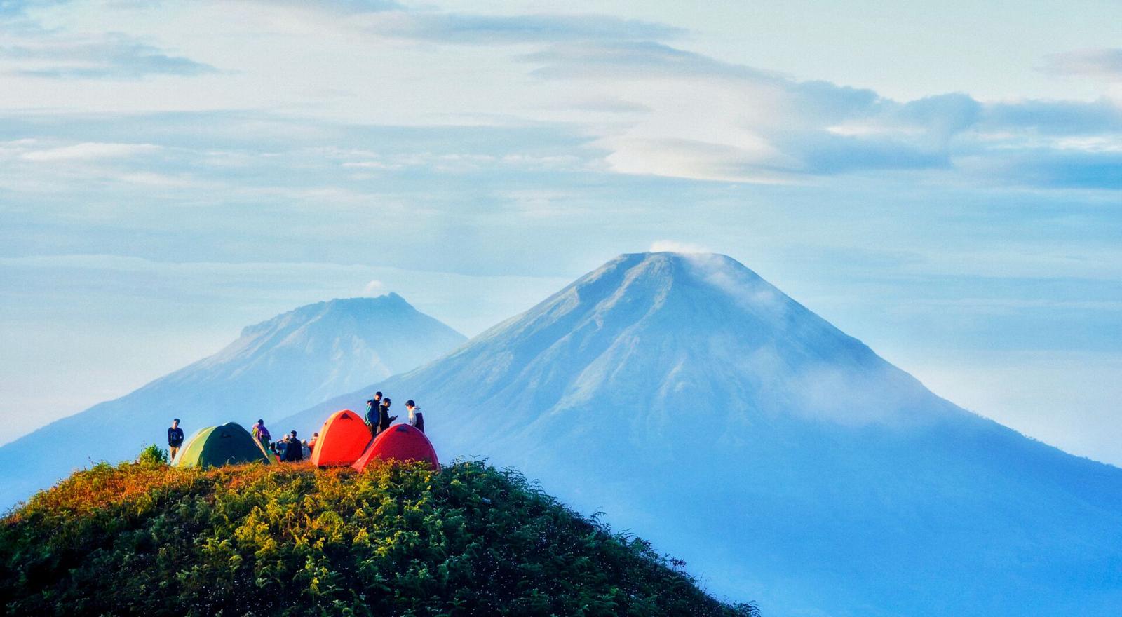 Large Web and Screen Group of campers sitting by their tents on top of a high mountain with a view of two volcanoes