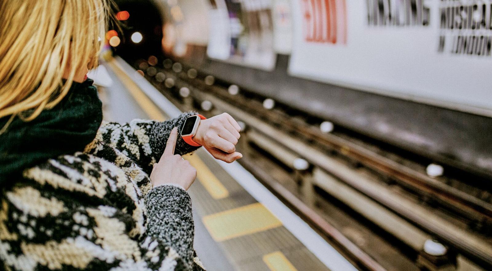 Large Web and Screen Woman looking at smartwatch on subway platform