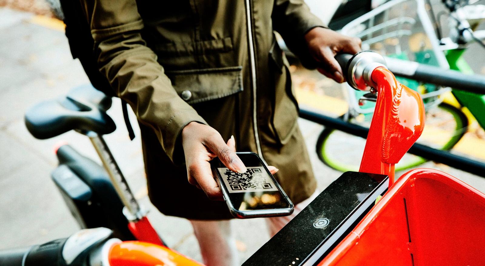 Large Web and Screen Woman using qr code on smart phone to rent share bike