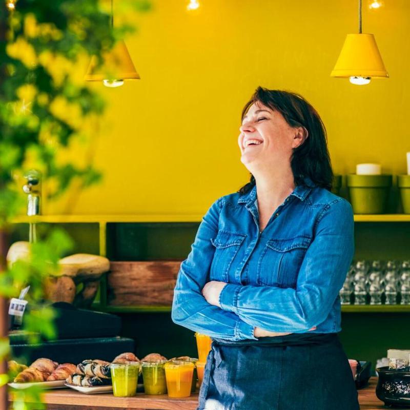 laughing young woman cafe owner standing by a yellow wall