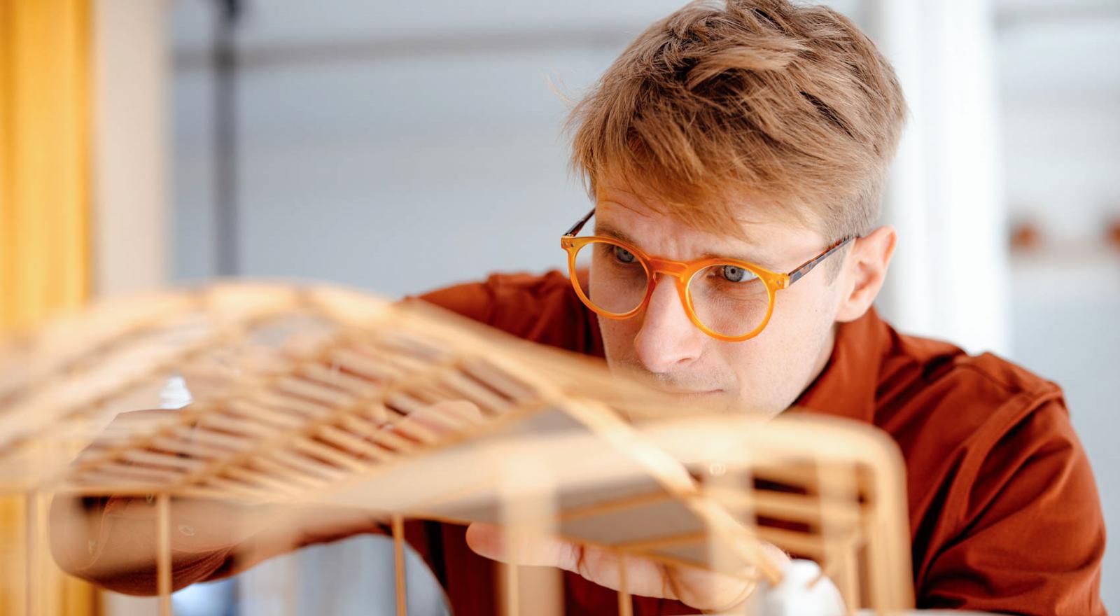 Man in orange glasses looking at a model of a building
