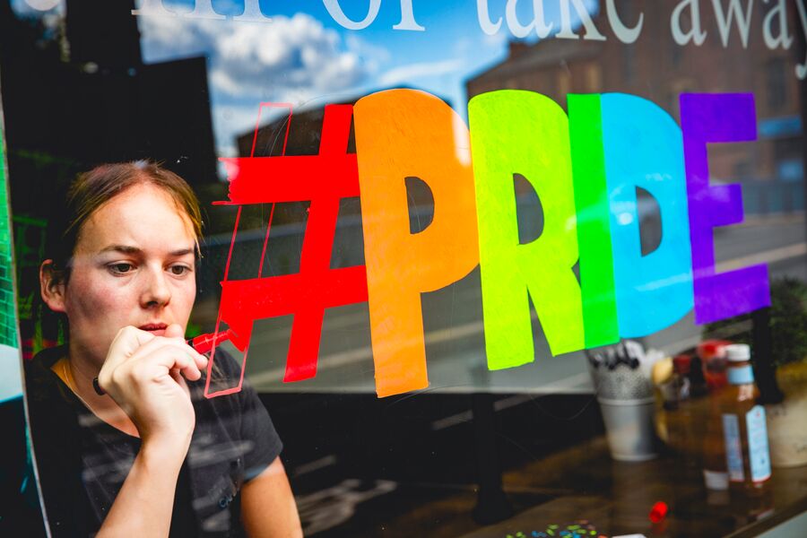 Medium Office 365 Young woman writing Pride in rainbow colours on a shop window