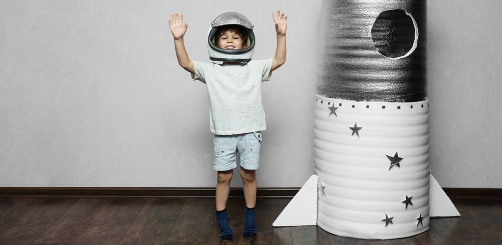 Child is wearing astronaut suit next to the rocket