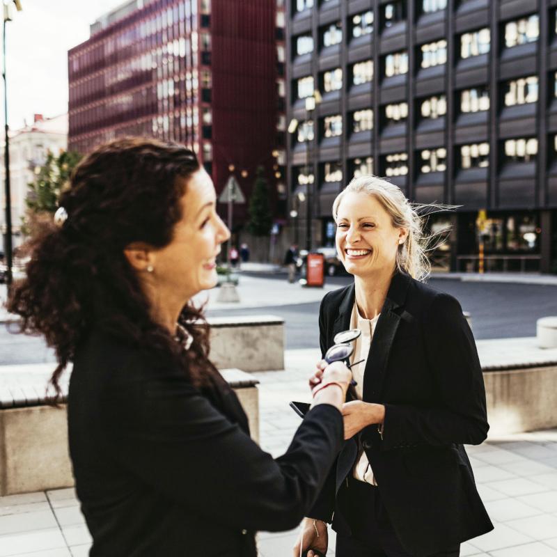 Three people are chatting and laughing outside on the street