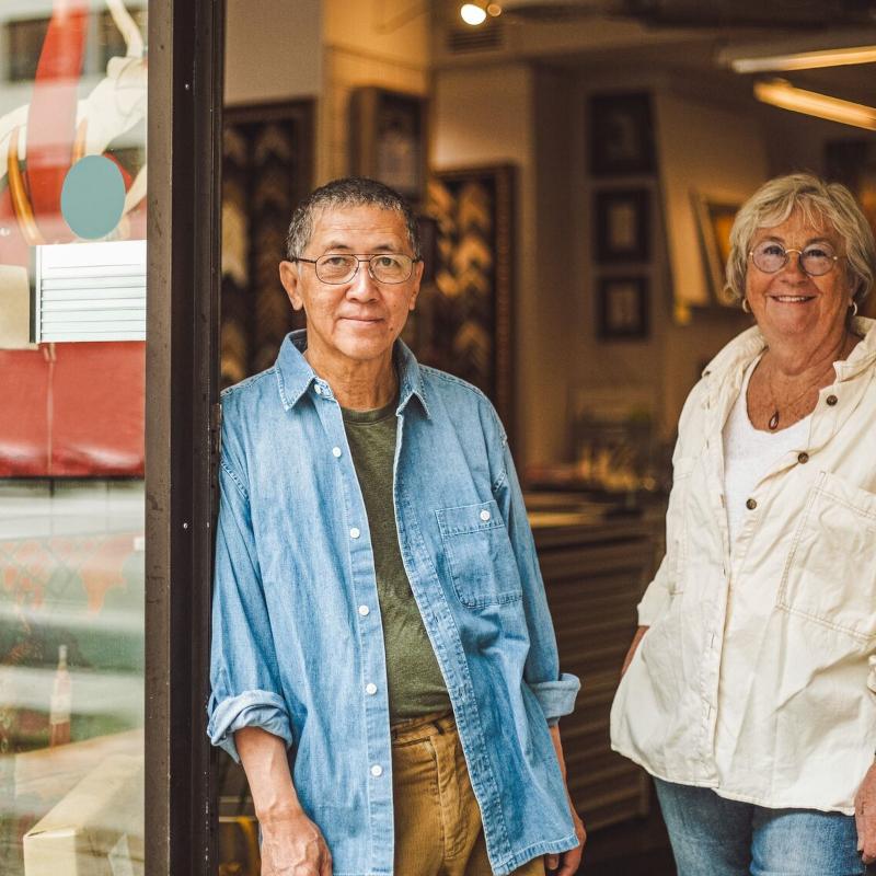Two business owners stand in the doorway of their store