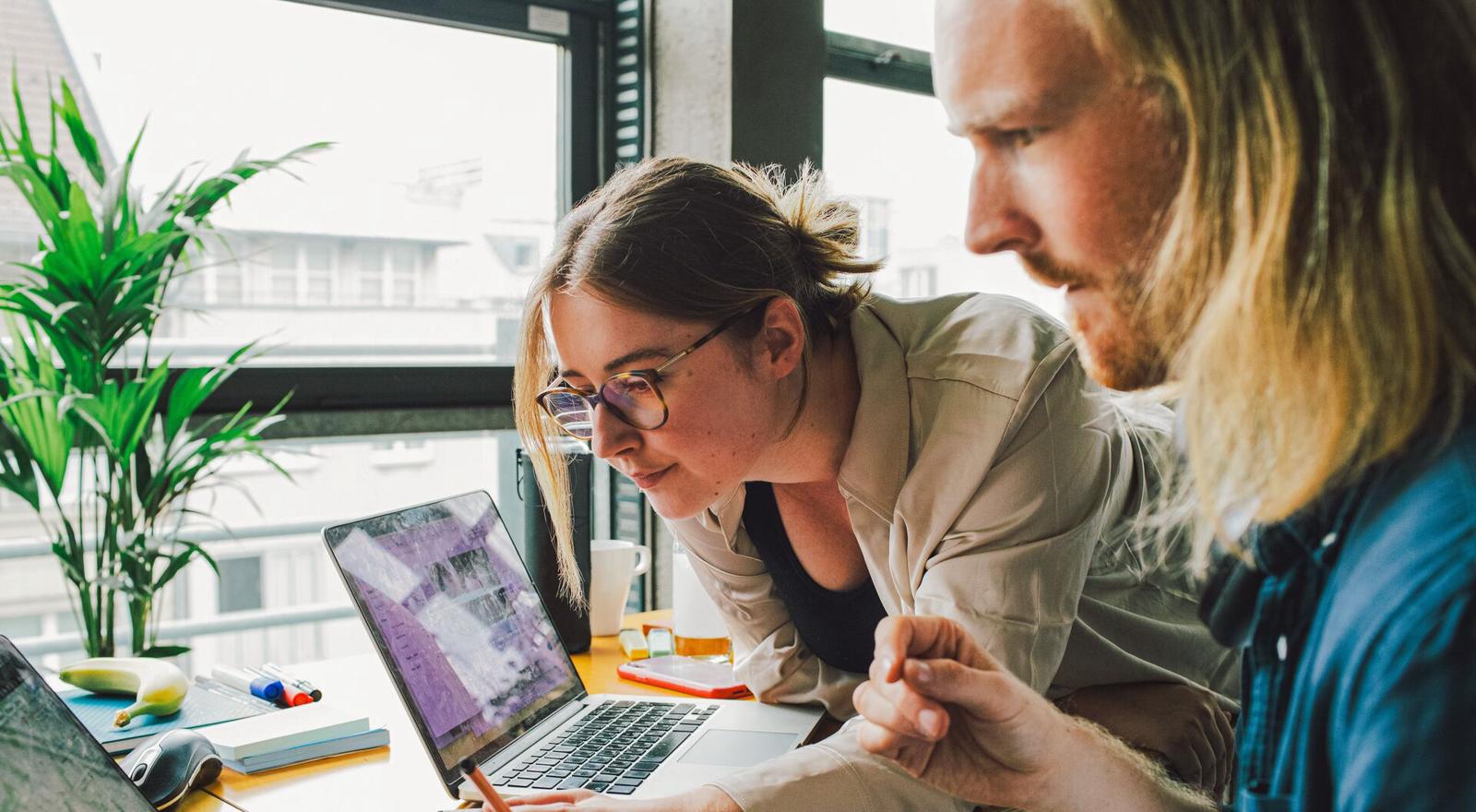 Two young colleagues review laptop