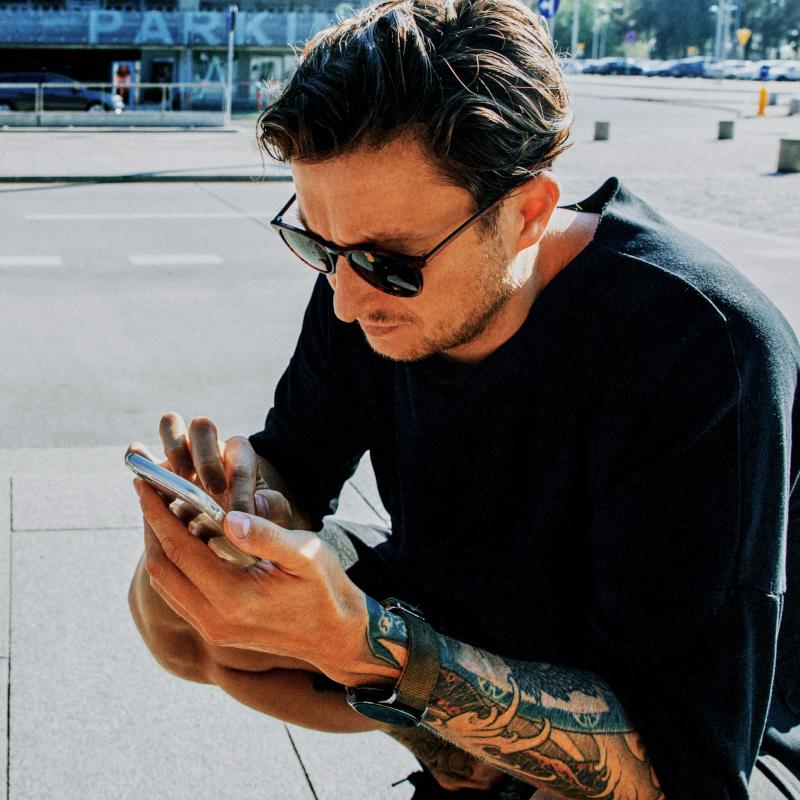 Young man using mobile phone while sitting 800x800